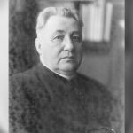 Black-and-white portrait of a middle-aged man wearing clerical clothing, looking at the camera.