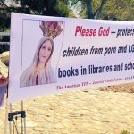 People outside holding a large banner that says, 'Please God—protect our children from porn and LGBTQ books in libraries and schools.'