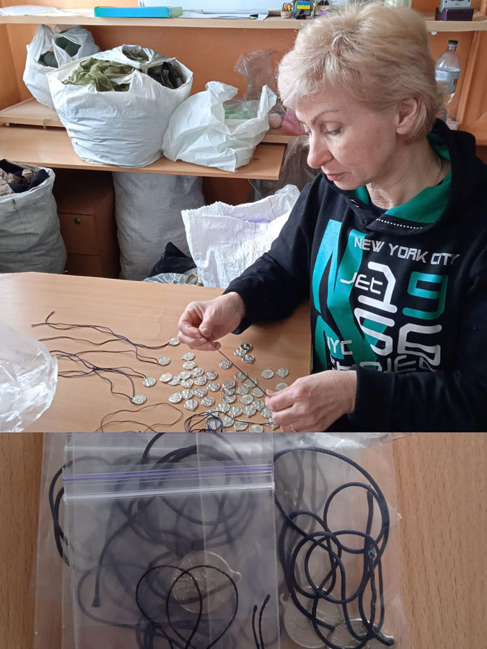 Woman at a table threading coins onto cords to make jewelry; coins and material bags are visible in the background.