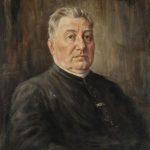 Portrait of an older man in a black clerical suit, looking to the side, seated indoors with a calm expression.